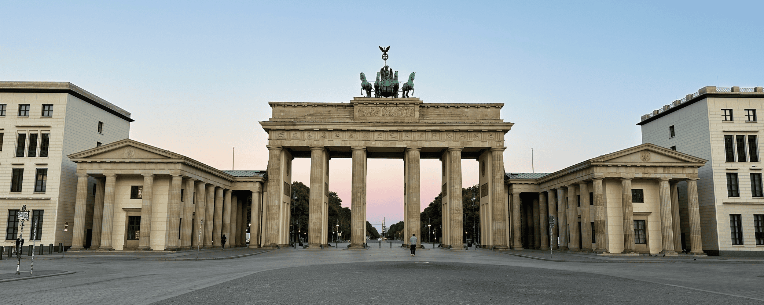 Brandenburg Gate, Berlin Frontal view of Berlin’s Brandenburg Gate, with its neoclassical columns and the quadriga statue silhouetted against the morning sky
