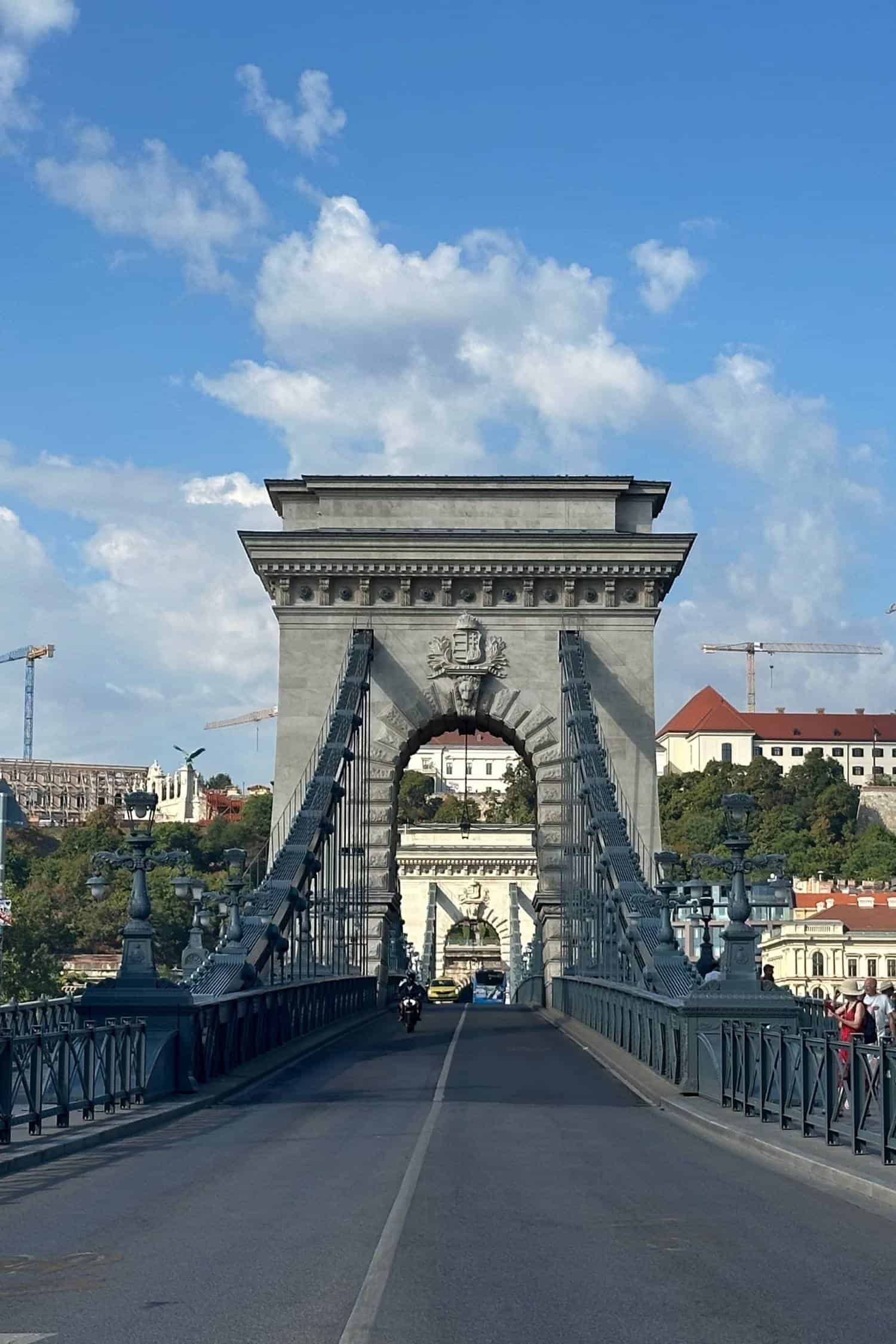 Széchenyi Chain Bridge leading to Buda Castle, Budapest View across Budapest’s Széchenyi Chain Bridge toward the Buda Castle District, framed by stone lions and suspension chains on a clear day.