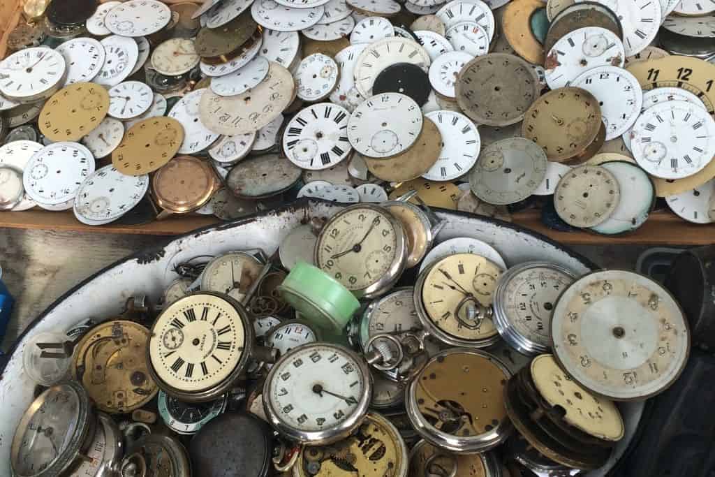 A collection of vintage watch dials and brass parts displayed at the Naschmarkt flea market in Vienna.