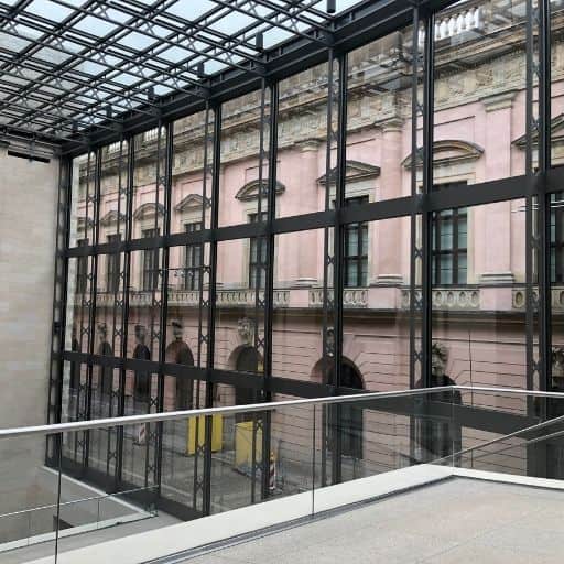 Glass-and-steel interior of the I. M. Pei extension at Berlin’s German Historical Museum, framing the Baroque rear façade of the Zeughaus.