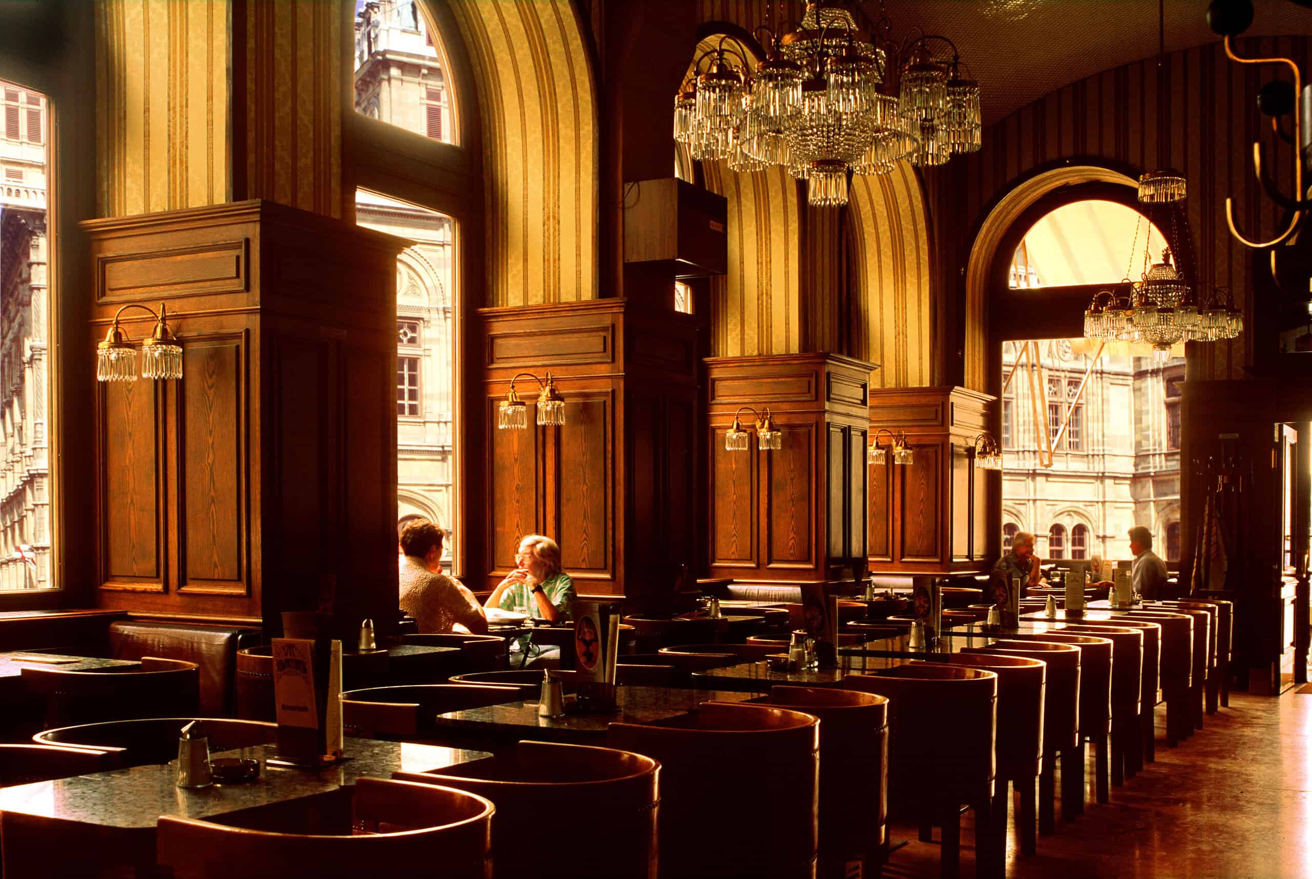 Café Schwarzenberg, Vienna — historic coffeehouse interior Café Schwarzenberg interior with arched windows, wood-paneled walls, chandeliers, and marble tables