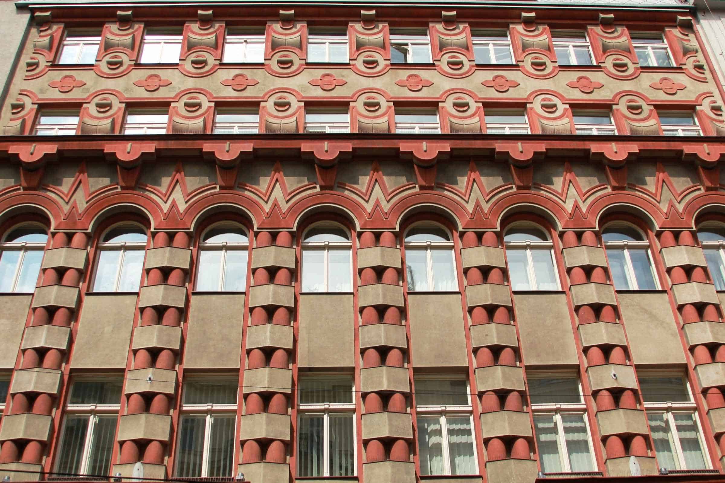 Rondocubist façade of Cukrárna Myšák on Vodičkova Street, Prague, with red-and-cream geometric ornament and arched windows