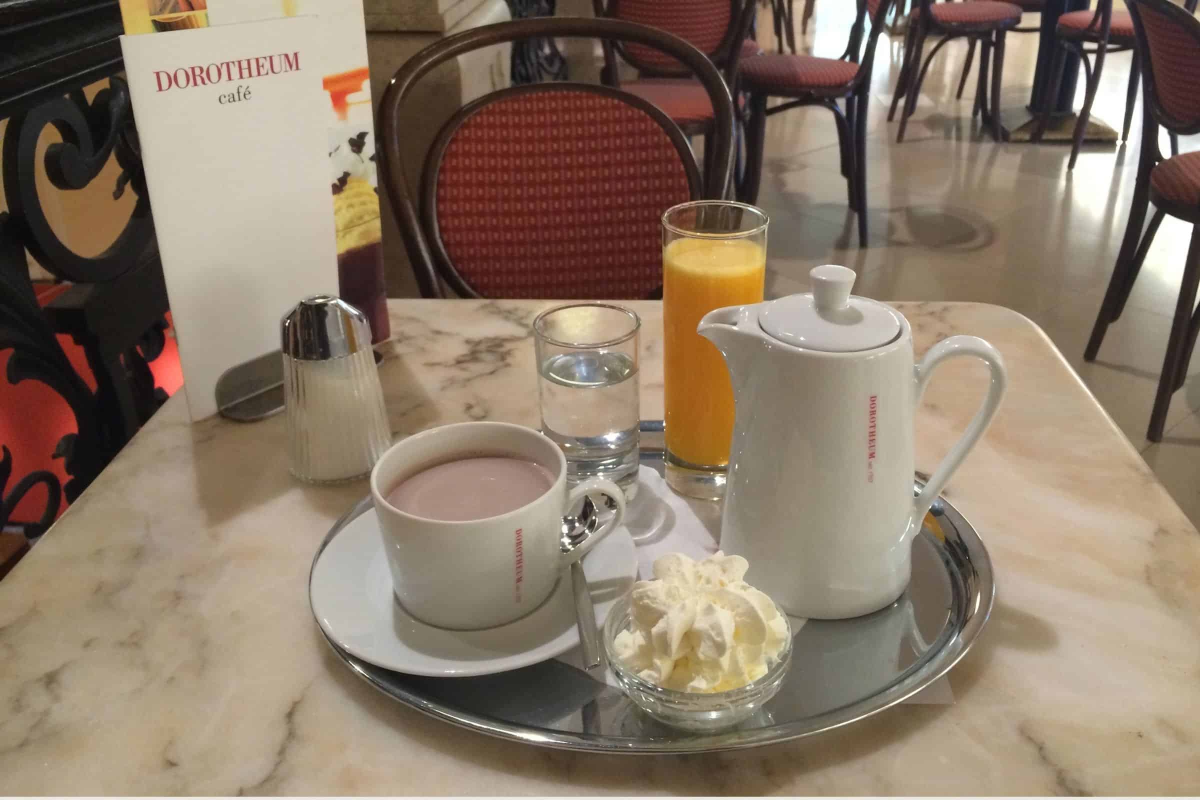 Café Dorotheum hot chocolate and classic Viennese service Hot chocolate served at Café Dorotheum in Vienna with whipped cream, orange juice, and porcelain service on a marble table