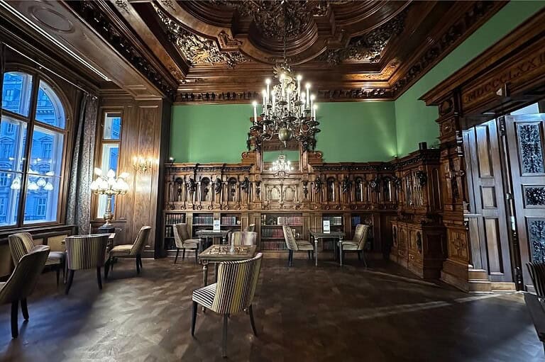 Side salon at Gerstner Café in Vienna with carved wood paneling chandeliers and upholstered chairs