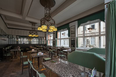 Interior of Grand Café Orient in Prague showcasing Cubist design with geometric furnishings, patterned tables, and tall windows overlooking the street