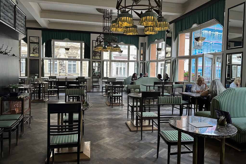 Grand Cafe Orient Prague interior with cubist lighting, striped banquettes, and tall windows