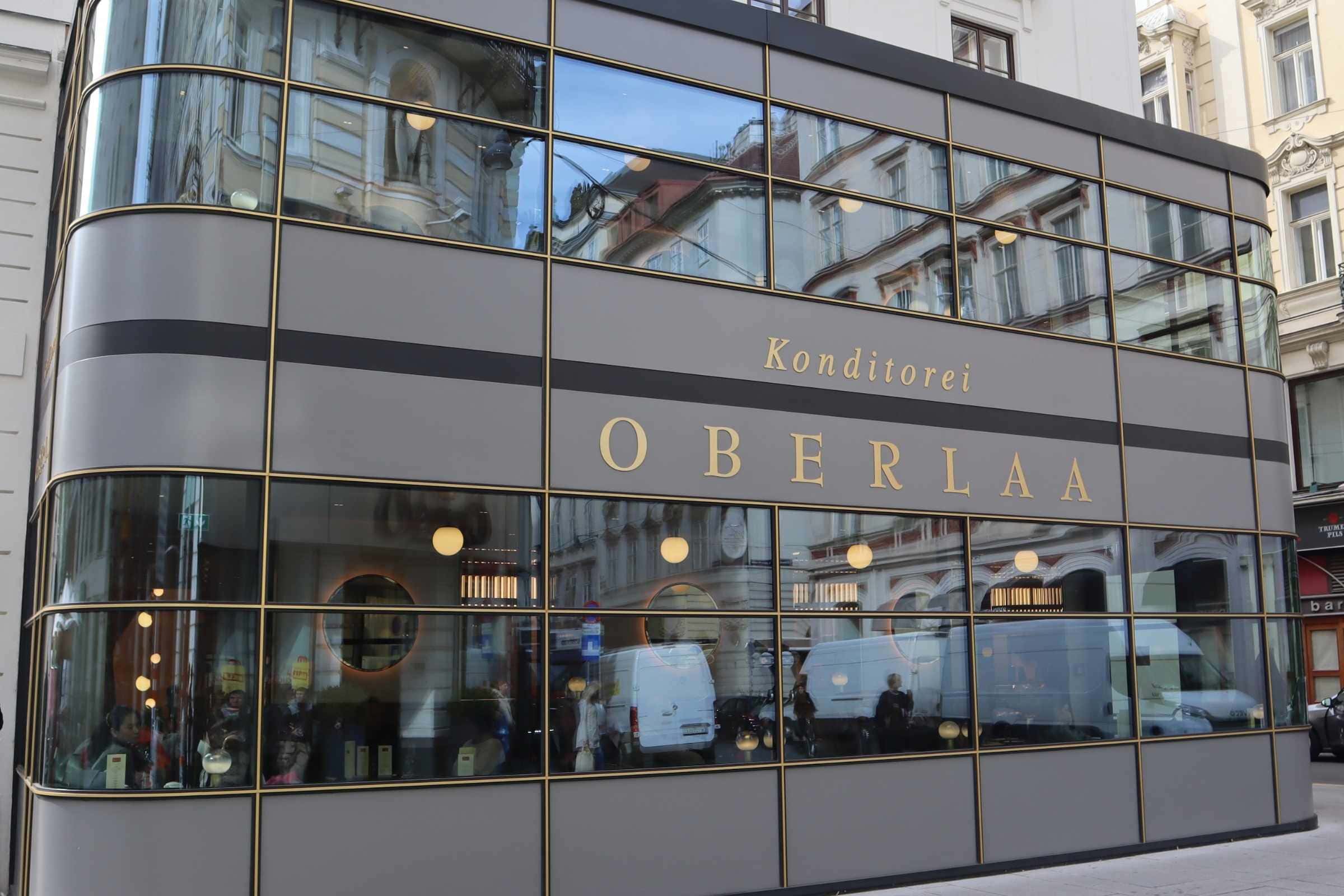 Konditorei Oberlaa, Vienna — modern façade of the historic pastry café Exterior of Konditorei Oberlaa in Vienna, with a curved glass façade and gold-lettered signage