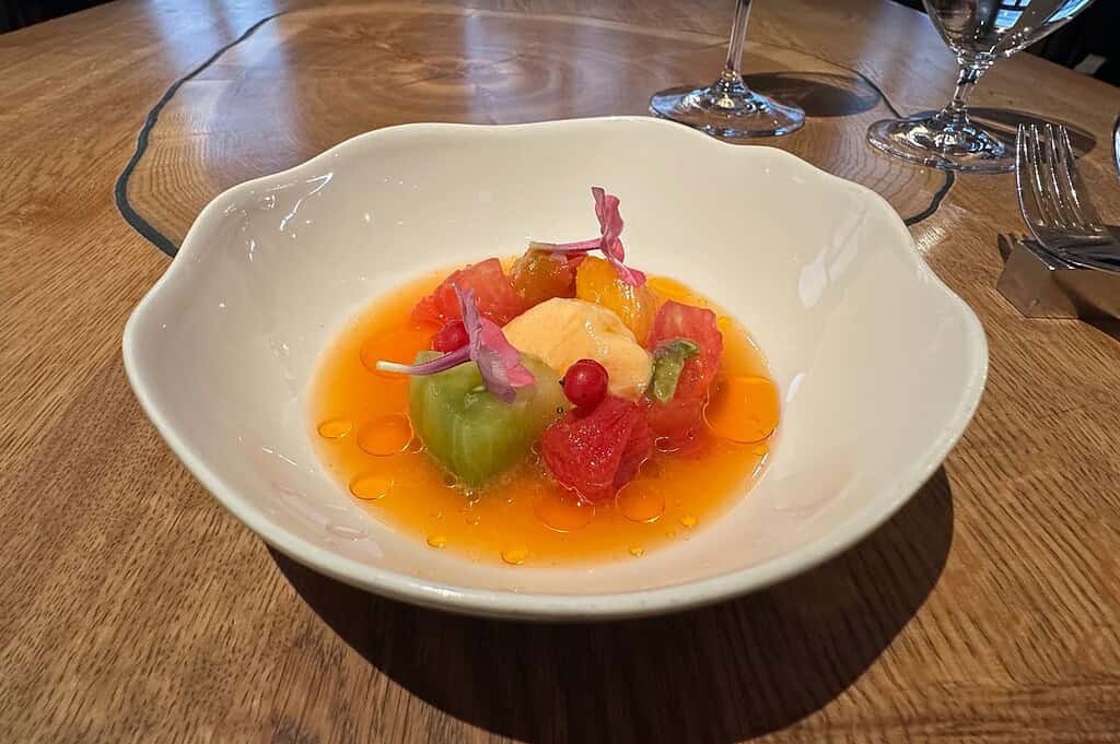 Photo gallery of La Degustation Bohême Bourgeoise in Prague, featuring the restaurant’s vaulted dining room and a progression of plated courses, from savory preparations to a fruit-forward dish, reflecting its modern approach to Czech cuisine.