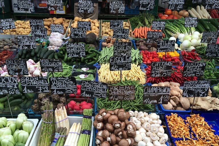 Fresh produce stalls at Vienna’s Naschmarkt with handwritten price signs and seasonal vegetables