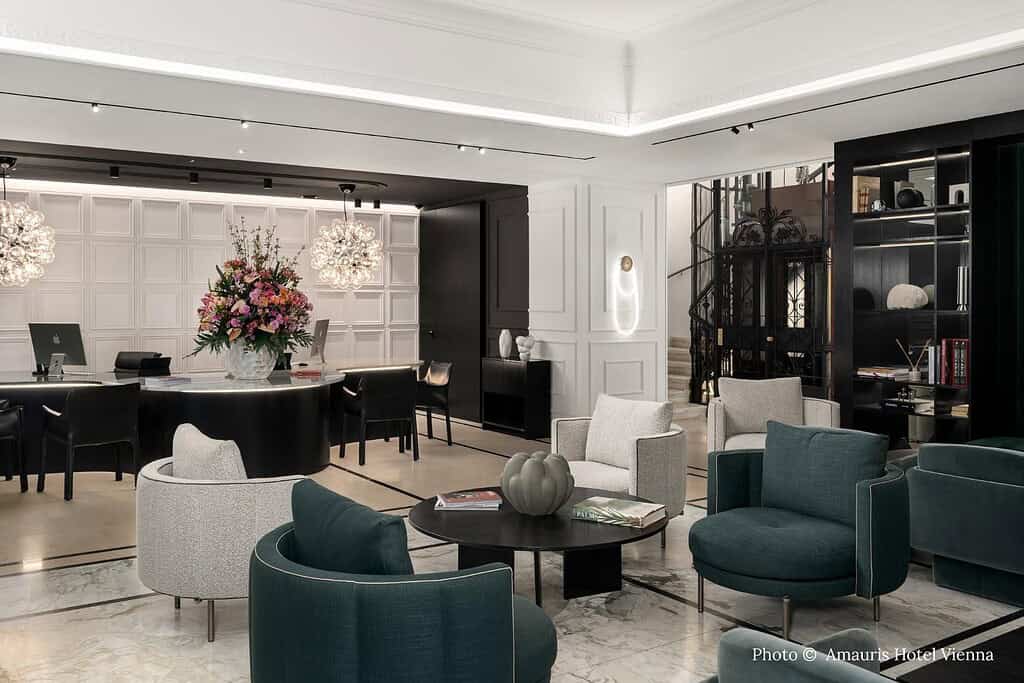 Amauris Hotel Vienna exterior near the Vienna State Opera with contemporary lobby seating and an Opera Suite featuring a red velvet headboard and crystal chandelier
