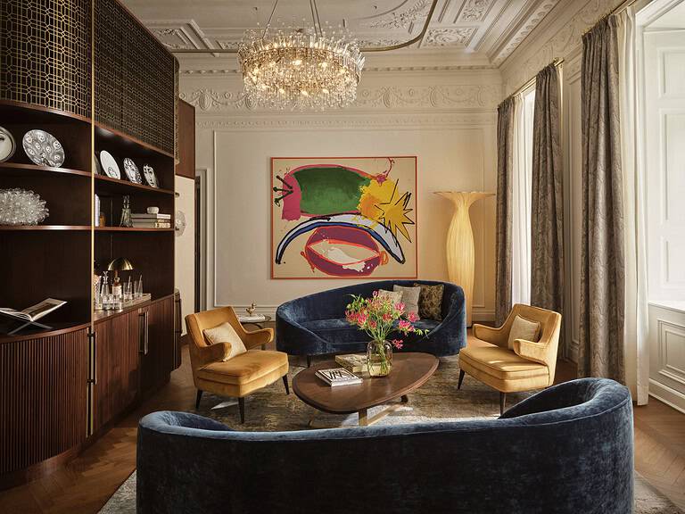 Graben House suite at Rosewood Vienna featuring velvet seating, crystal chandelier, and contemporary art within historic architectural detailing