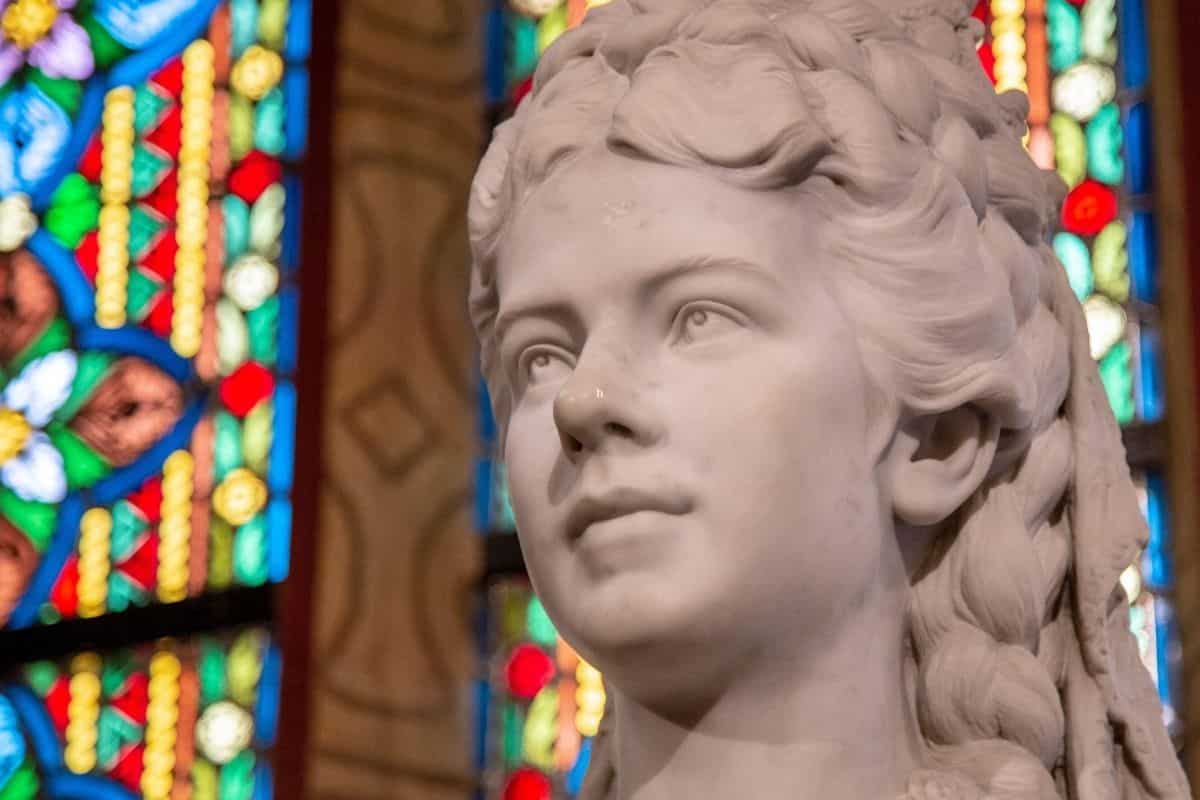 Close-up of a sculpture of Empress Elisabeth of Austria in Matthias Church, Budapest, with colorful stained glass behind her