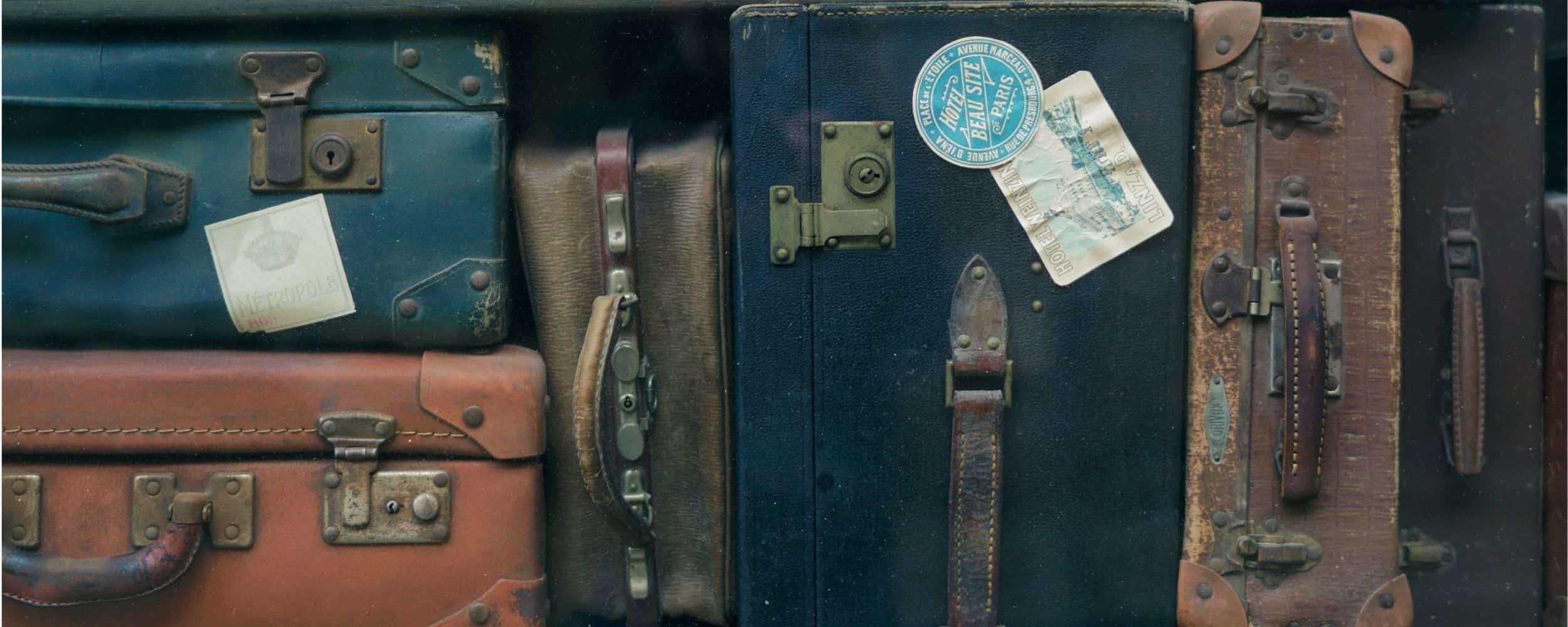 Stack of vintage leather suitcases with European hotel and travel stickers