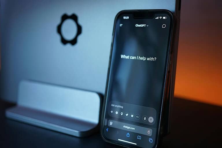 ChatGPT open on a smartphone beside a laptop during AI-assisted trip planning