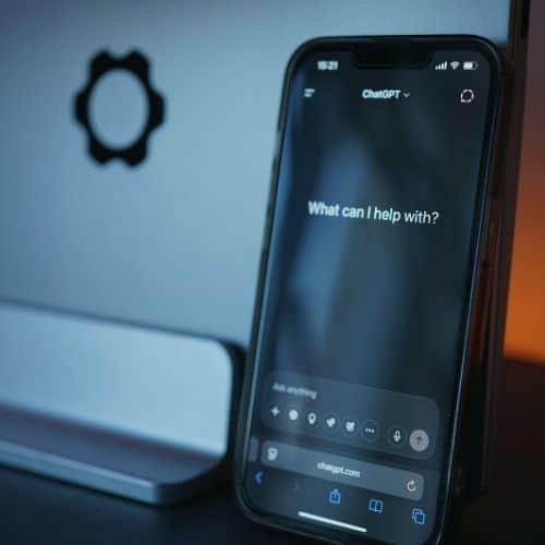 Smartphone displaying the ChatGPT interface beside a laptop, illustrating AI-assisted travel planning