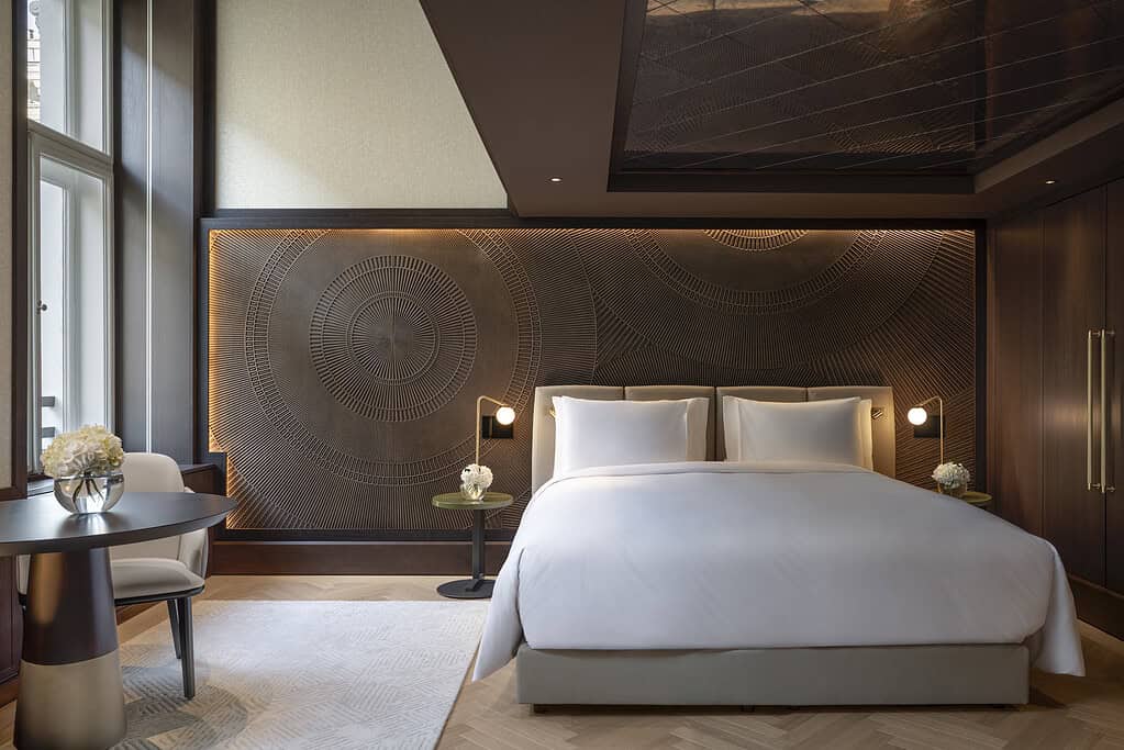 Guest room at Almanac Palais Vienna with contemporary furnishings and a large sculptural wall panel behind the bed.