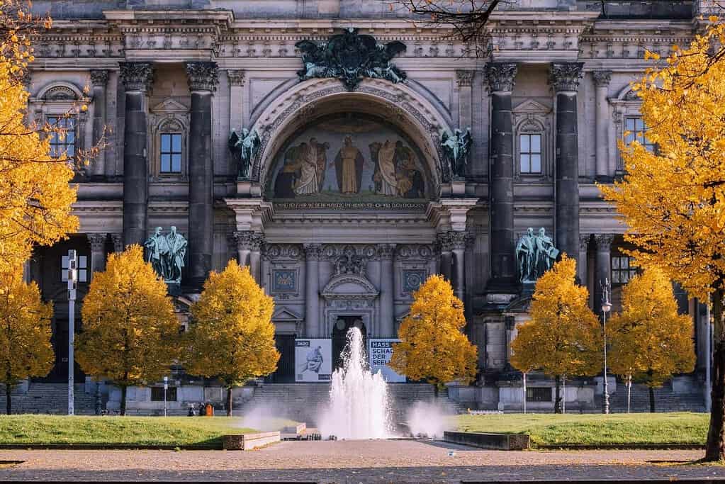 Berliner Dom framed by golden autumn trees beside a fountain in central Berlin
