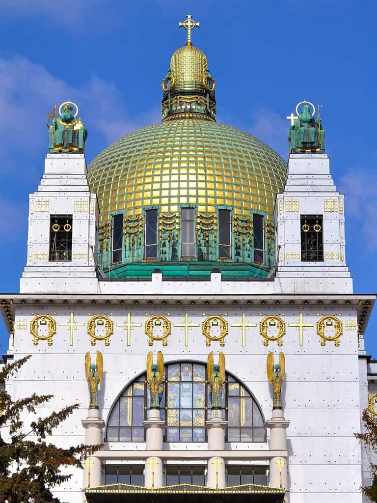 Exterior of Otto Wagner’s Kirche am Steinhof in Vienna, showing the white façade, gilded details, angel statues, and distinctive copper-and-gold dome