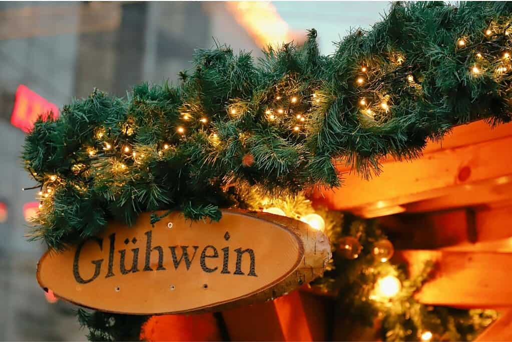 Sign at a stall offering hot mulled wine at a Christmas market in Vienna, Austria with pine  and white light decorations