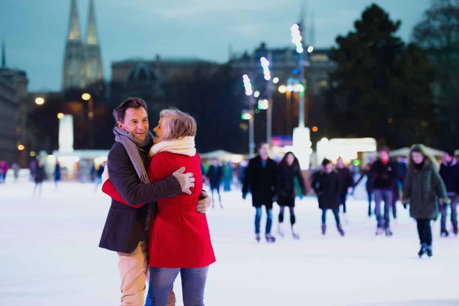 Couple propping each other up amid other ice-skaters at a Christmas market in Vienna Austria